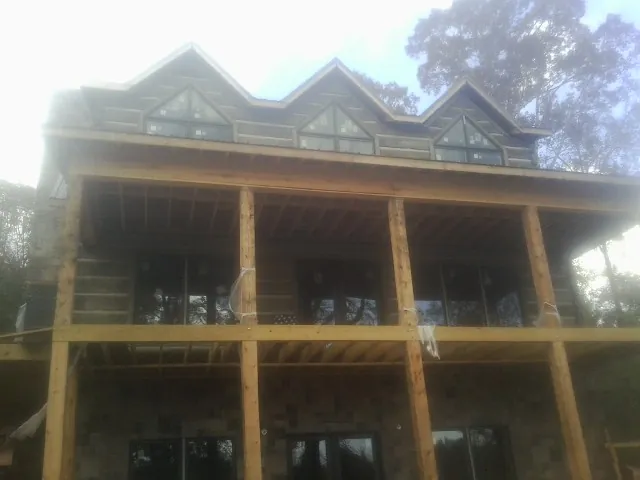 Dormers and porch framing on a large log home under construction — Roof Coating work by our crew in Marengo