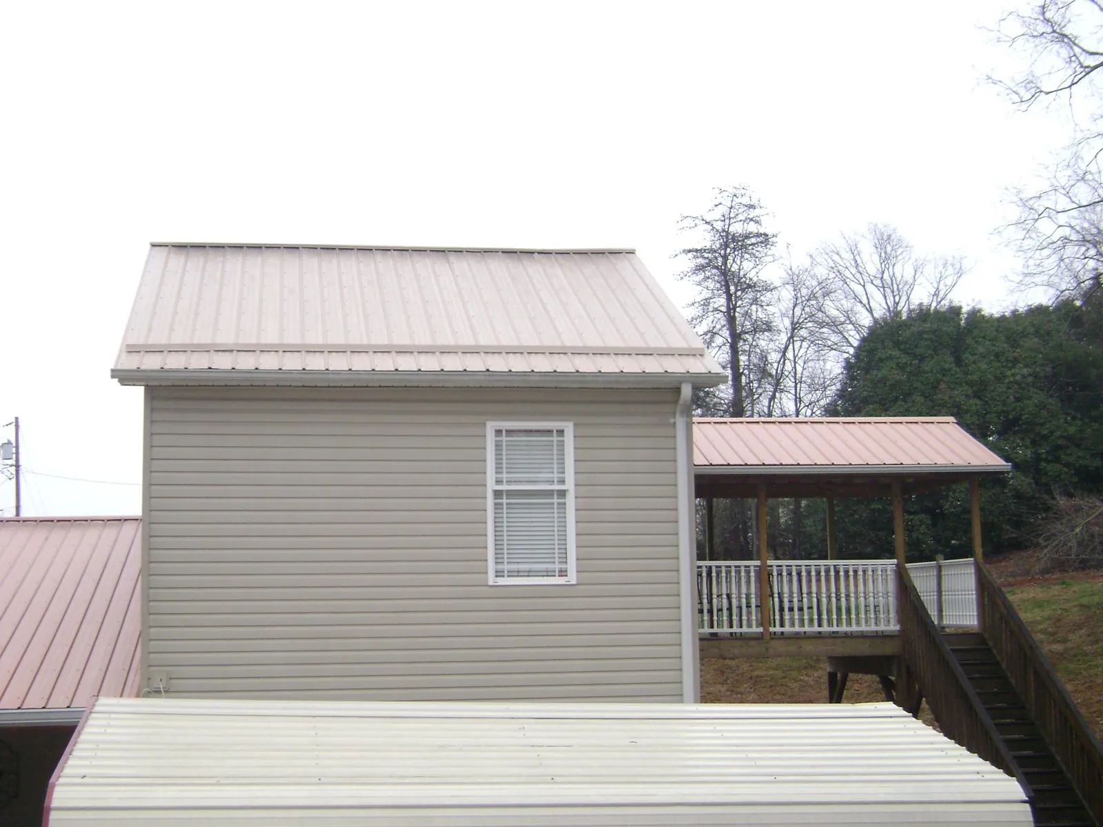 Tan metal roofs on a two story addition and attached porch, from a Roof Replacement job in Marengo