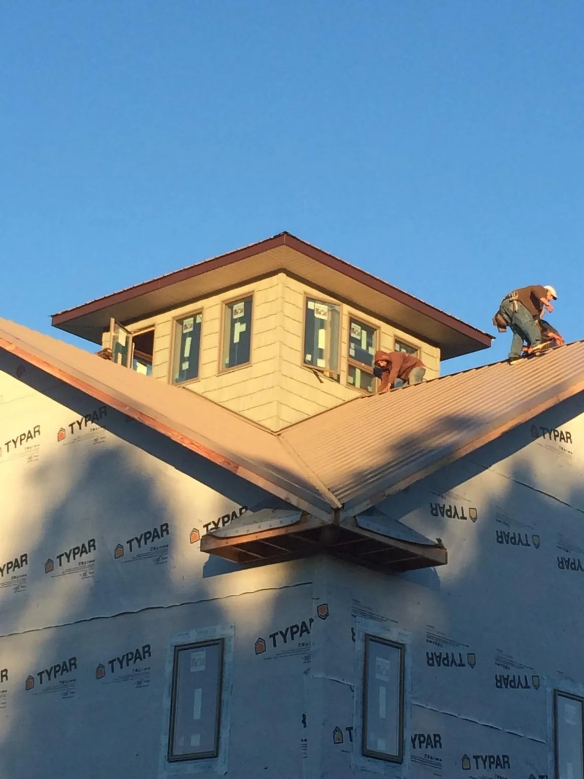 Roofers working around a rooftop cupola on a new metal roof at sunset — Roof Waterproofing in Marengo by Roofing Brothers